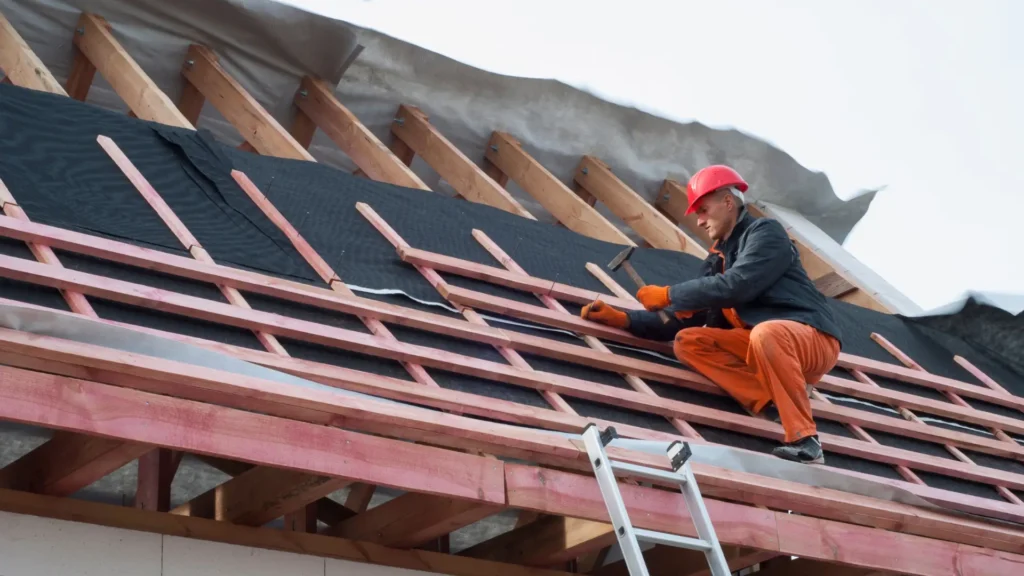 Membrana dachowa pod blachę - zdjęcie przedstawia specjalistę, który montuje membranę dachową na krokwiach pod dach blaszany